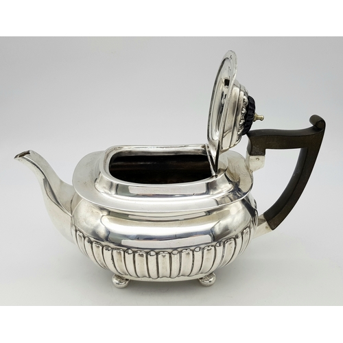 188 - An Antique Sterling Silver Teapot. Part fluted body, bun feet and an angular wooden handle. Hallmark... 