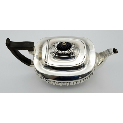 188 - An Antique Sterling Silver Teapot. Part fluted body, bun feet and an angular wooden handle. Hallmark... 