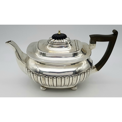 188 - An Antique Sterling Silver Teapot. Part fluted body, bun feet and an angular wooden handle. Hallmark... 