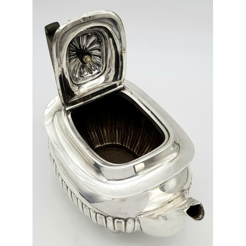 188 - An Antique Sterling Silver Teapot. Part fluted body, bun feet and an angular wooden handle. Hallmark... 