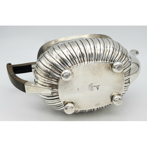 188 - An Antique Sterling Silver Teapot. Part fluted body, bun feet and an angular wooden handle. Hallmark... 