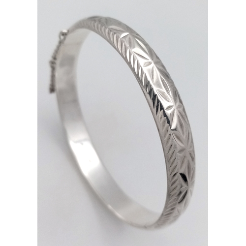 406 - A vintage hinged silver bangle. Complete with silver safety chain. Beautiful decoration to front. UK... 