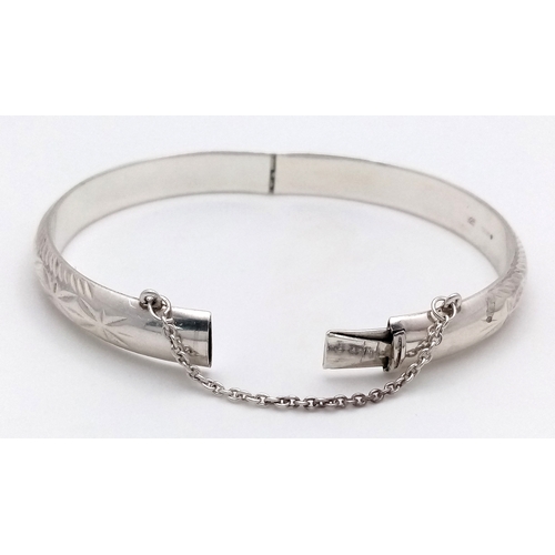406 - A vintage hinged silver bangle. Complete with silver safety chain. Beautiful decoration to front. UK... 