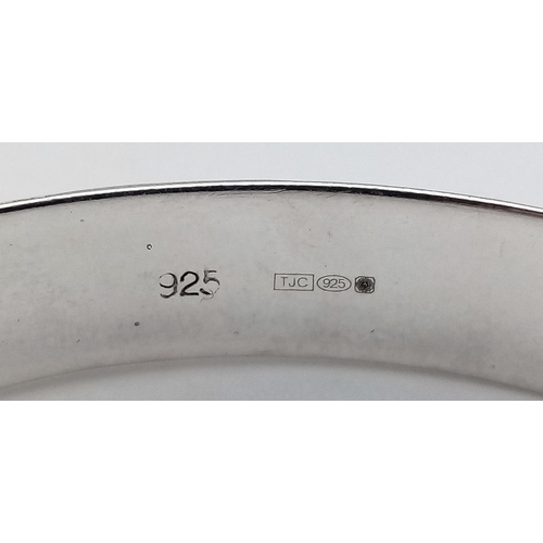 406 - A vintage hinged silver bangle. Complete with silver safety chain. Beautiful decoration to front. UK... 