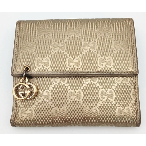 395 - A Gucci Gold GG Canvas Trifold Wallet. Crafted in gold-tone GG monogram canvas with leather trim and... 