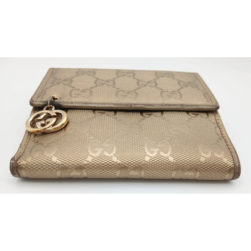 395 - A Gucci Gold GG Canvas Trifold Wallet. Crafted in gold-tone GG monogram canvas with leather trim and... 