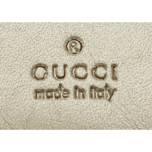 395 - A Gucci Gold GG Canvas Trifold Wallet. Crafted in gold-tone GG monogram canvas with leather trim and... 