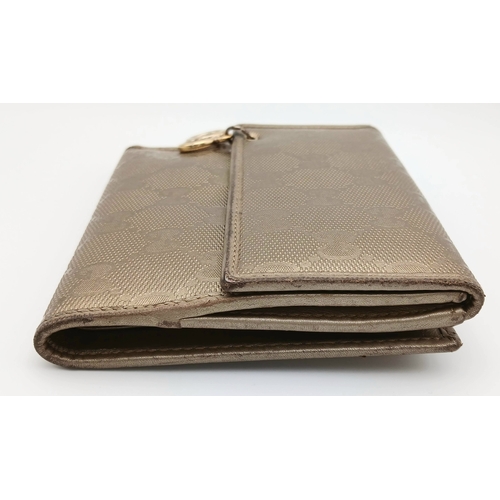 395 - A Gucci Gold GG Canvas Trifold Wallet. Crafted in gold-tone GG monogram canvas with leather trim and... 