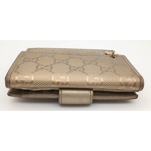 395 - A Gucci Gold GG Canvas Trifold Wallet. Crafted in gold-tone GG monogram canvas with leather trim and... 
