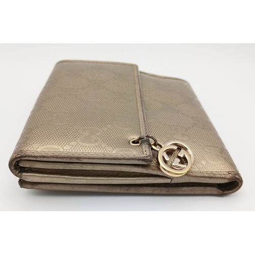 395 - A Gucci Gold GG Canvas Trifold Wallet. Crafted in gold-tone GG monogram canvas with leather trim and... 