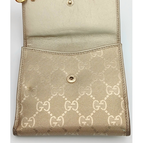 395 - A Gucci Gold GG Canvas Trifold Wallet. Crafted in gold-tone GG monogram canvas with leather trim and... 