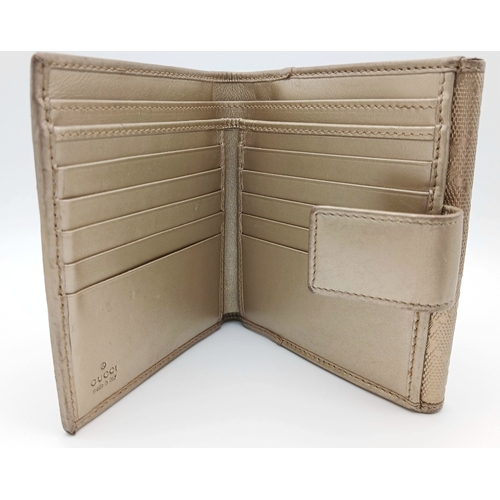 395 - A Gucci Gold GG Canvas Trifold Wallet. Crafted in gold-tone GG monogram canvas with leather trim and... 