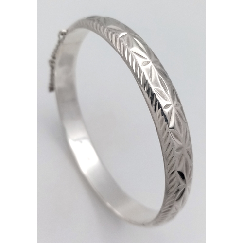 406 - A vintage hinged silver bangle. Complete with silver safety chain. Beautiful decoration to front. UK... 