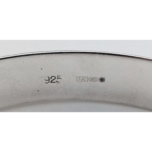 406 - A vintage hinged silver bangle. Complete with silver safety chain. Beautiful decoration to front. UK... 