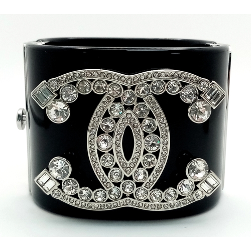 125 - A Chanel Black CC Embellished Cuff Bangle. Set with white stones. 5.5cm width. 58mm inner diameter. ... 