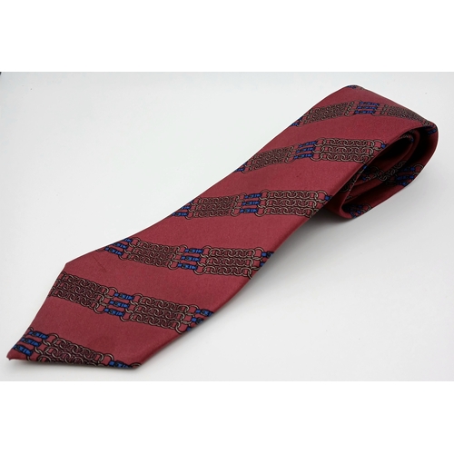 498 - An Hermès silk tie. Crafted in burgundy silk featuring a repeating chain and link motif in contrasti... 