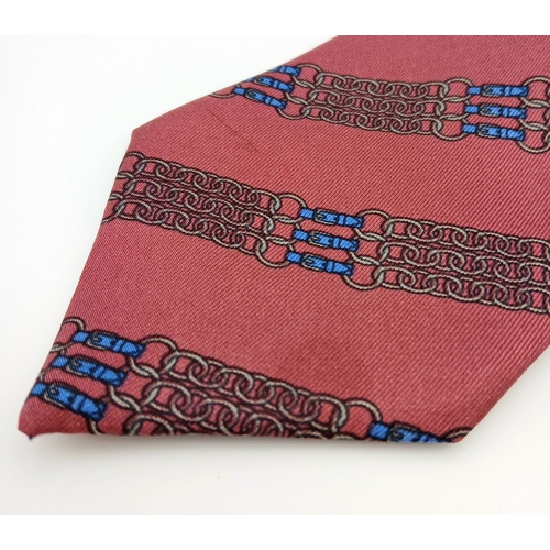 498 - An Hermès silk tie. Crafted in burgundy silk featuring a repeating chain and link motif in contrasti... 