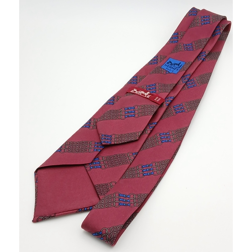 498 - An Hermès silk tie. Crafted in burgundy silk featuring a repeating chain and link motif in contrasti... 