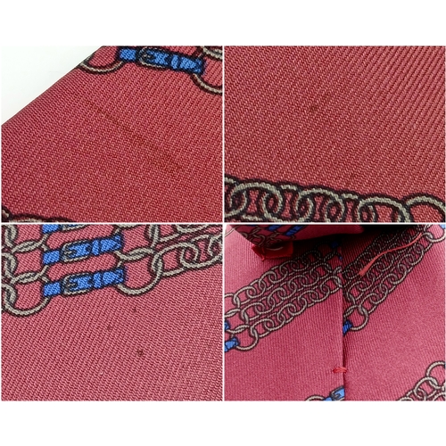 498 - An Hermès silk tie. Crafted in burgundy silk featuring a repeating chain and link motif in contrasti... 
