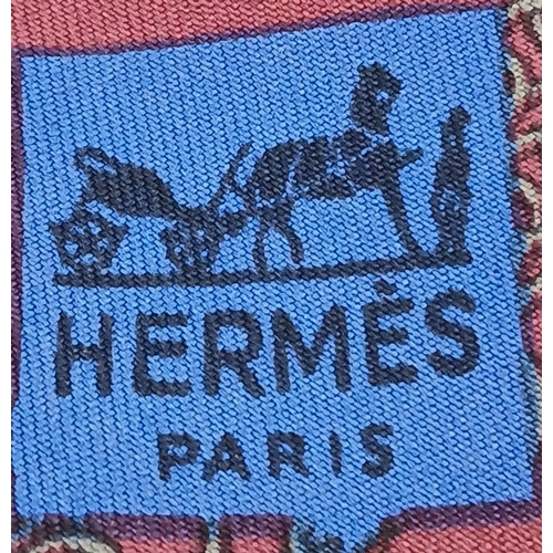 498 - An Hermès silk tie. Crafted in burgundy silk featuring a repeating chain and link motif in contrasti... 