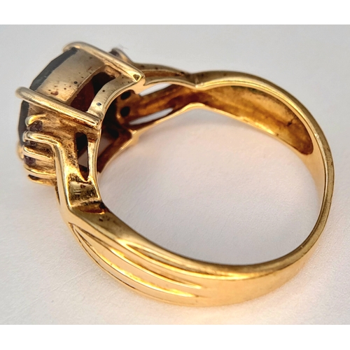 175 - A 9K Yellow Gold Garnet Ring. A cushion cut garnet c.2ct sits on a raised setting with garnet accent... 