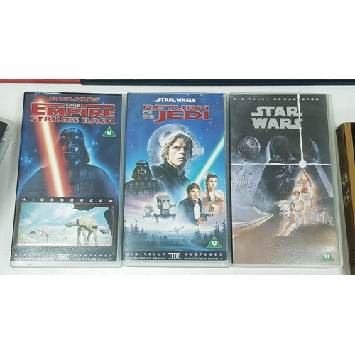 81 - A bundle of Star Wars collectables. To include three framed posters, VHS videos, DVD's, figures and ... 