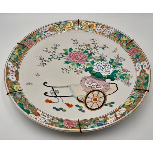 309 - An Antique Chinese Porcelain Decorative Charger. Famille rose design with a floral cart scene. Marki... 