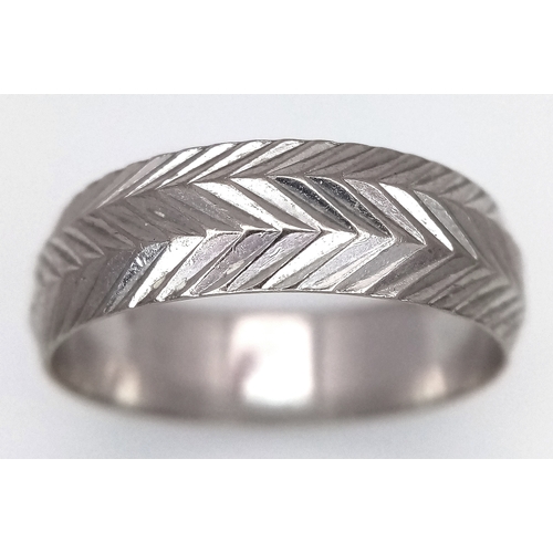 3 - An 18K White Gold Band Ring. Textured chevron exterior band pattern. Size T 1/2. 7mm width. 5.6g.