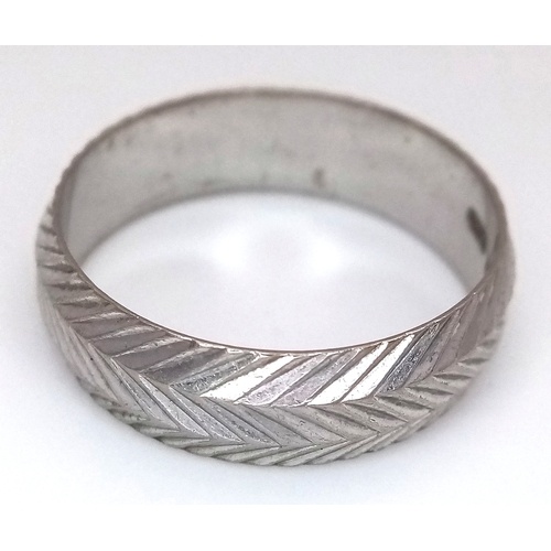 3 - An 18K White Gold Band Ring. Textured chevron exterior band pattern. Size T 1/2. 7mm width. 5.6g.