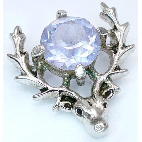 71 - A Deer Head Brooch with Blue Stone. Set with a central round-cut blue stone within a stag head desig... 