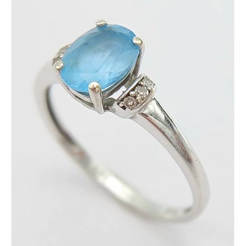 1162 - An Attractive 9K White Gold Blue Topaz and Diamond Set Ring Size M1/2. The Ring is set with a 7mm Lo... 