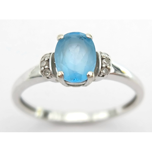 1162 - An Attractive 9K White Gold Blue Topaz and Diamond Set Ring Size M1/2. The Ring is set with a 7mm Lo... 