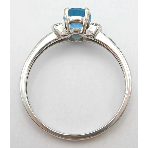 1162 - An Attractive 9K White Gold Blue Topaz and Diamond Set Ring Size M1/2. The Ring is set with a 7mm Lo... 