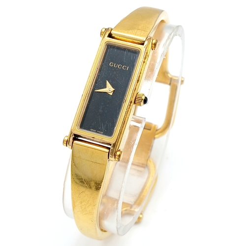 649 - A LADIES GUCCI, GOLD TONE BANGLE WATCH. MODEL 1500L. IN FULL WORKING ORDER, NEW BATTERY FITTED RECEN... 