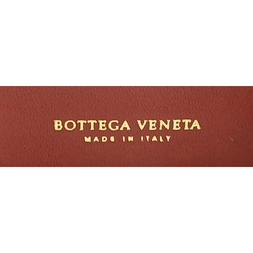 1241 - A Bottega Veneta Burgundy Wallet. Intrecciato leather exterior with gold-toned hardware, zipped coin... 