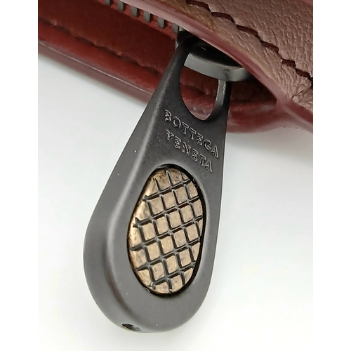 1241 - A Bottega Veneta Burgundy Wallet. Intrecciato leather exterior with gold-toned hardware, zipped coin... 