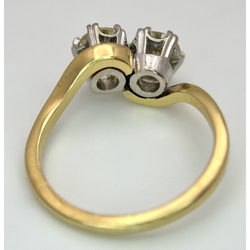 674 - An 18K Yellow Gold Diamond Crossover Ring. A 1ct round brilliant cut diamond having I colour and com... 