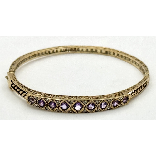 93 - A VINTAGE 9K GOLD HINGED BANGLE WITH DECORATIVE SIDES AND DIAMOND AND AMETHYST TOP STONES .    13.2g... 