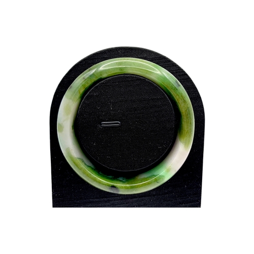 704 - A Green Jade Bangle，circular form, carved from jade of variegated green and pale tones. Inner diamet... 