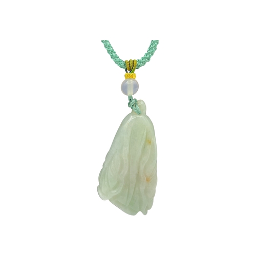 725 - A Jade Pendant Necklace. The celadon-green jade pendant finely carved in a flowing, organic form, su... 
