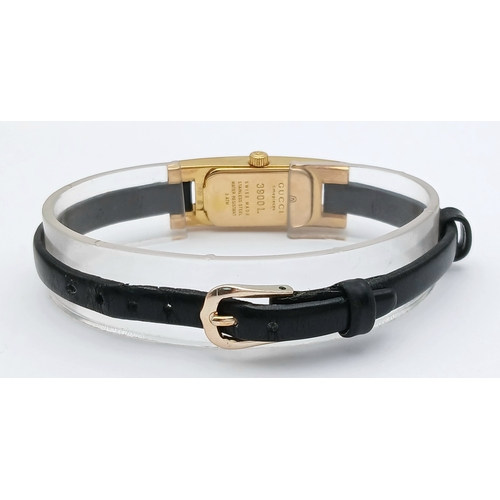 558 - A GUCCI, GOLD TONE, BLACK DIAL AND BLACK LEATHER STRAP WATCH. MODEL 3900L. IN FULL WORKING ORDER. S/... 