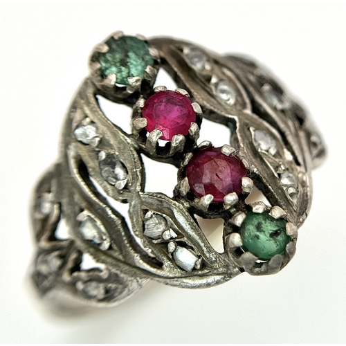 122 - An Antique Gold, Silver, Ruby and Emerald Ring. The band tests as 14k gold with an openwork silver s... 