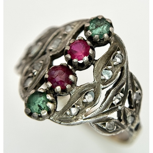 122 - An Antique Gold, Silver, Ruby and Emerald Ring. The band tests as 14k gold with an openwork silver s... 
