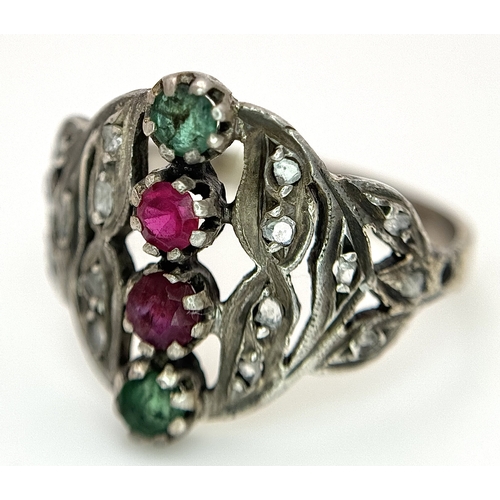 122 - An Antique Gold, Silver, Ruby and Emerald Ring. The band tests as 14k gold with an openwork silver s... 