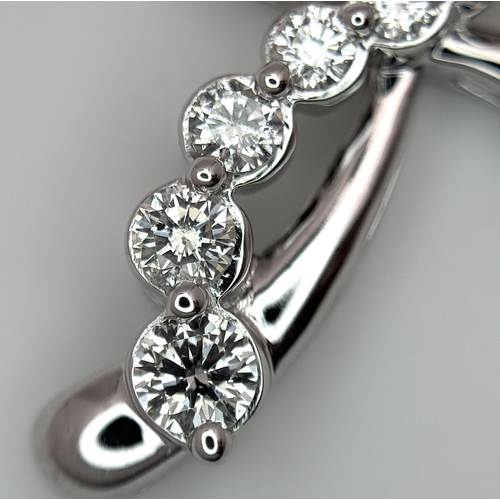 241 - A 14K White Gold Diamond Cross Pendant. c.0.60ctw of round brilliant cut diamonds having G-H colour ... 