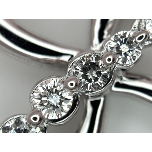 241 - A 14K White Gold Diamond Cross Pendant. c.0.60ctw of round brilliant cut diamonds having G-H colour ... 