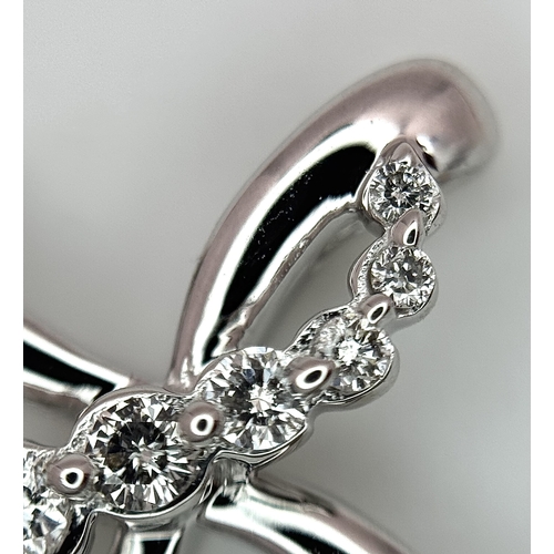 241 - A 14K White Gold Diamond Cross Pendant. c.0.60ctw of round brilliant cut diamonds having G-H colour ... 