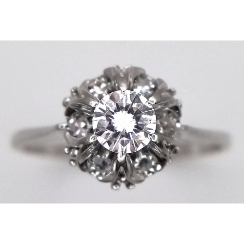 1213 - An 18K White Gold Diamond Cluster Ring. A 0.25ct round brilliant cut centre stone with a 0.20ctw dia... 