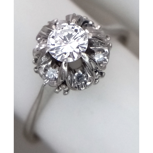 1213 - An 18K White Gold Diamond Cluster Ring. A 0.25ct round brilliant cut centre stone with a 0.20ctw dia... 