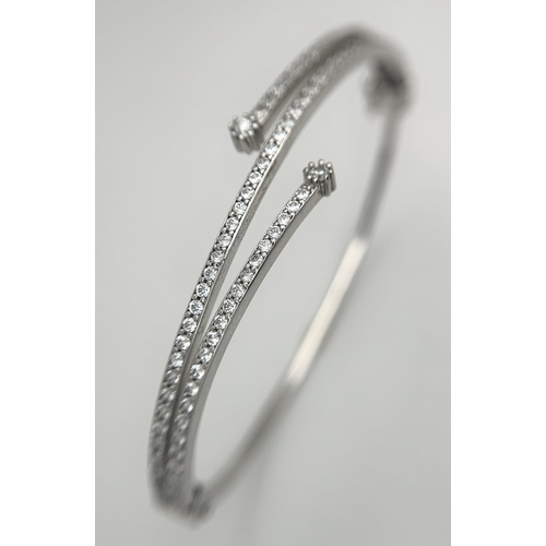 554 - A 14K White Gold and Diamond Crossover Bangle Bracelet. c.100 micro-claw pave set diamonds of c.1ctw... 